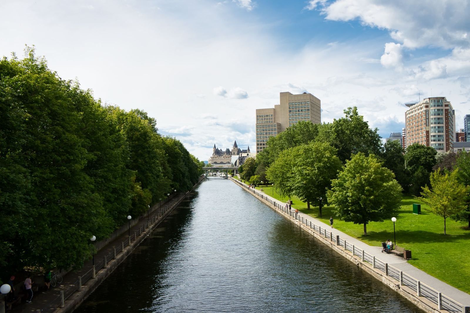 The Rideau Canal between parkland and downtown Ottawa under a blue sky
