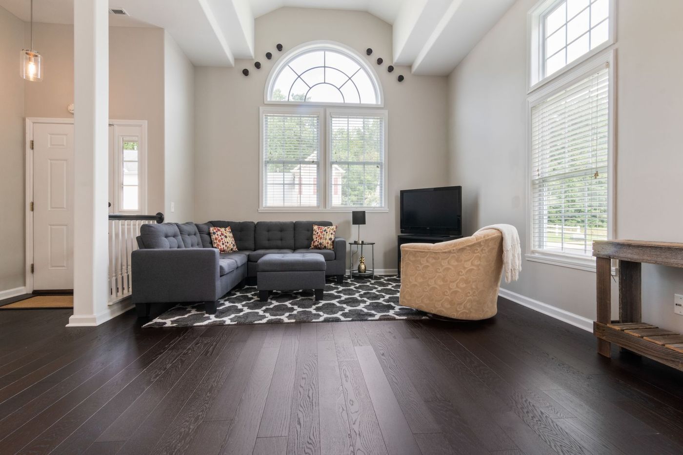 A living room with high ceilings, an arched window and a grey sofa