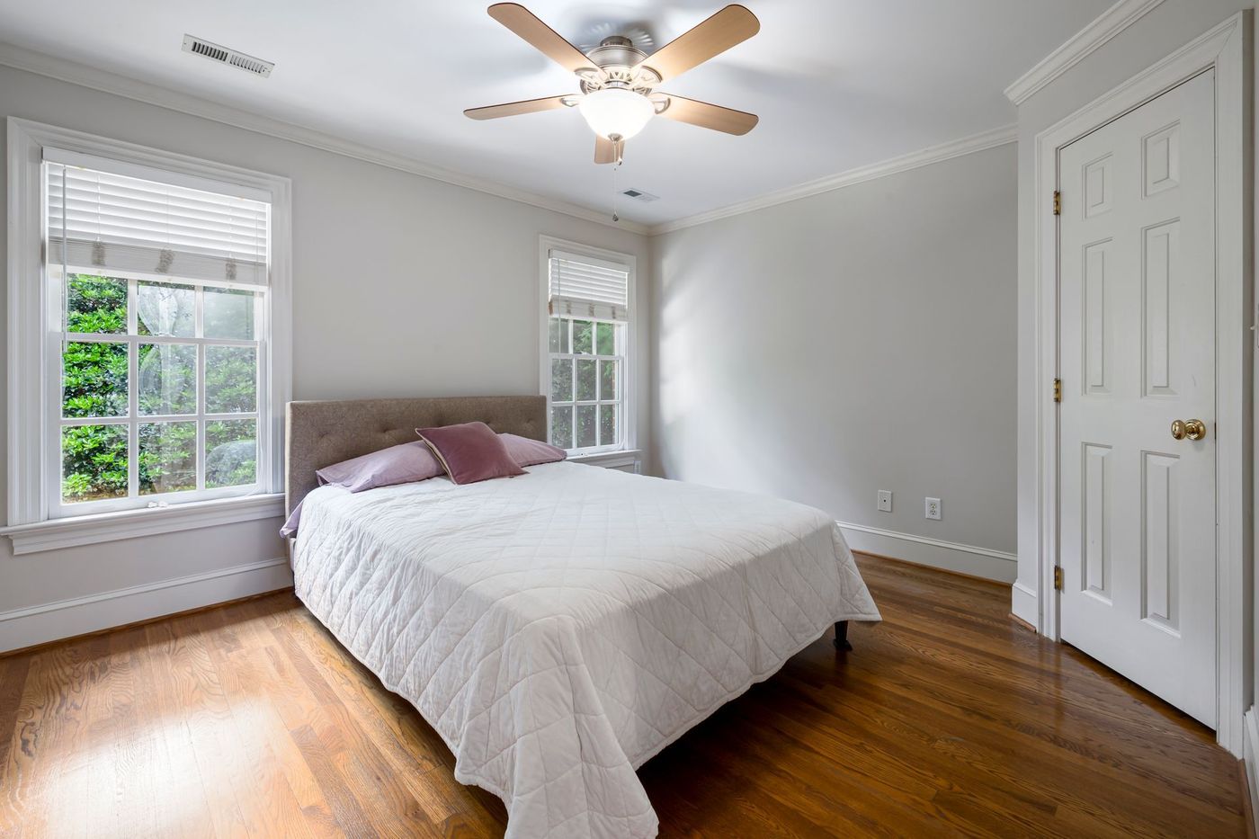 A bright bedroom with white linen and a ceiling fan
