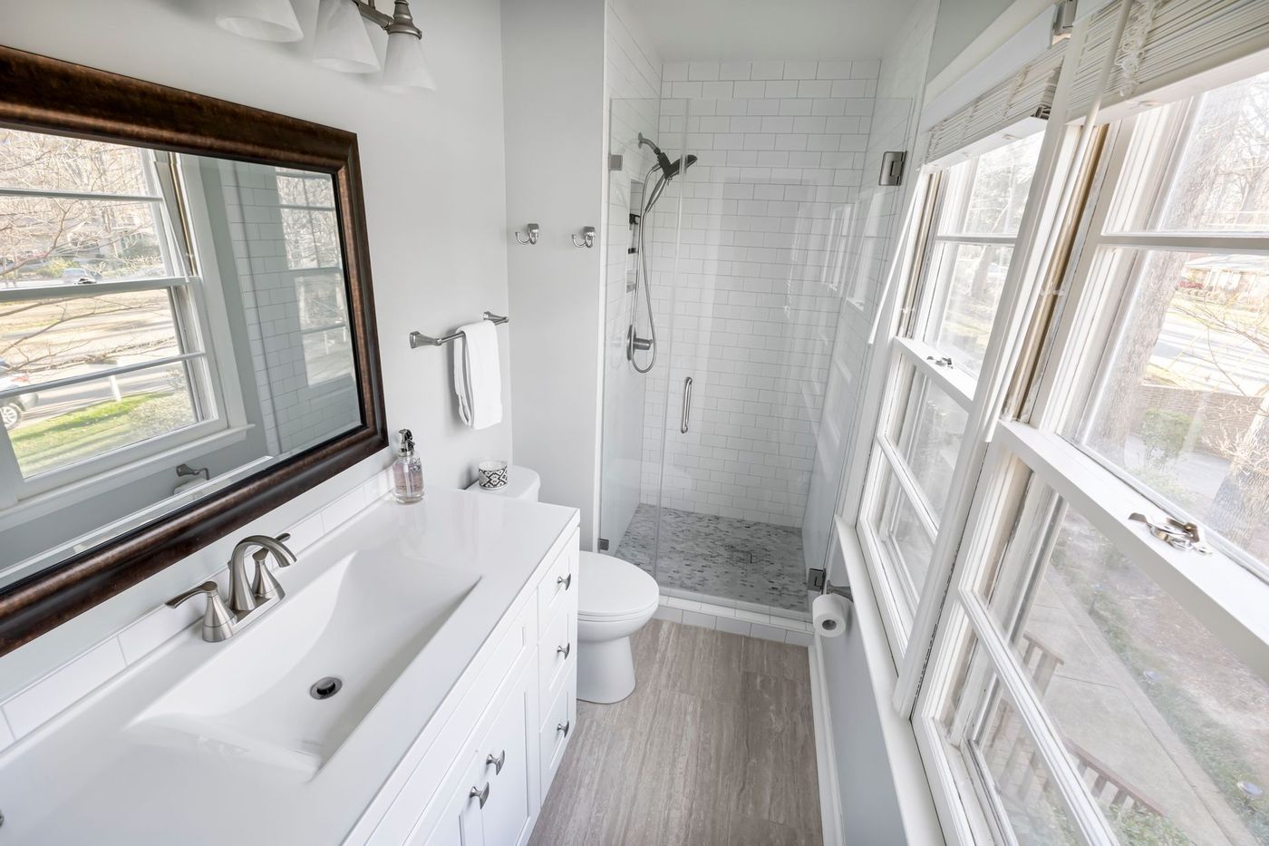 A white bathroom with a tiled shower and a window